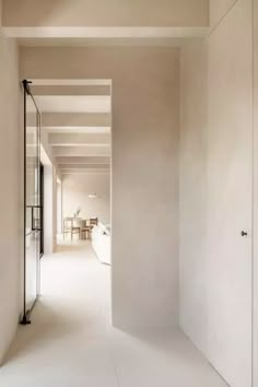 an empty hallway leading to a living room with white walls and flooring on both sides