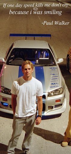 a man standing in front of a white car with blue stripes on it's hood