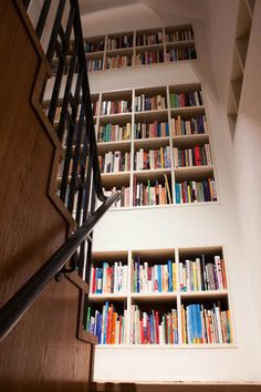 the bookshelves are filled with many different colored books and there is also a stair case