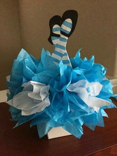 a vase filled with blue and white tissue pom poms on top of a wooden table