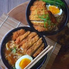 two black bowls filled with food and chopsticks