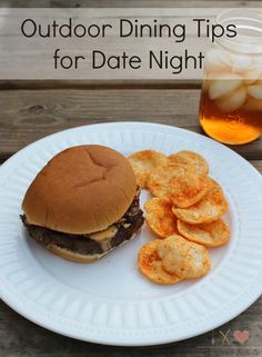 a white plate topped with a sandwich and potato chips next to a glass of beer