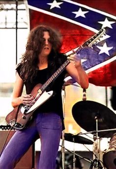 an image of a woman playing guitar on stage with the american flag in the background