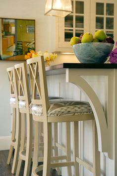 a kitchen island with two stools and a bowl of fruit on it