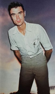 a man standing in front of a photo with his hands on his hips and looking at the camera