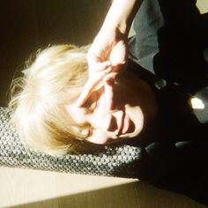 a woman laying on top of a wooden floor next to a black bag with her hands behind her head