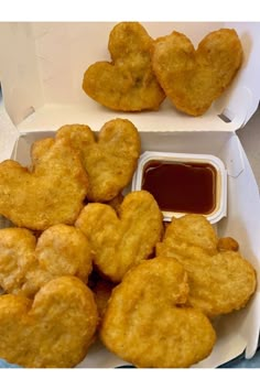 heart shaped pastries in a takeout container with ketchup and dipping sauce