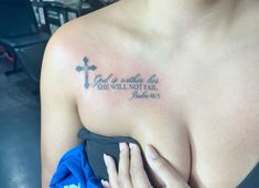 a woman's chest with a cross and bible verse tattooed on the upper part of her left arm