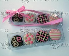 four decorated chocolates in a box with pink ribbon on the top and one is empty