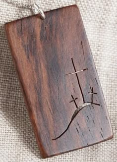 a wooden pendant with a cross on it sitting on a piece of cloth next to a string