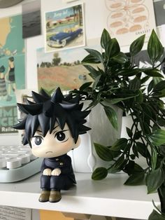 a figurine sitting on top of a desk next to a plant