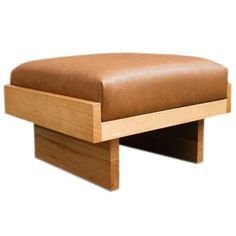 a brown leather ottoman sitting on top of a wooden table