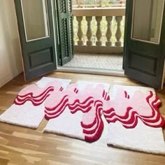 two rugs on the floor in front of an open door with red and white designs