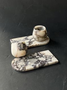 two marble coasters sitting on top of a black table next to a cup and saucer