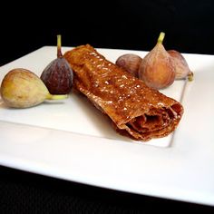 a white plate topped with food on top of a wooden table next to figs