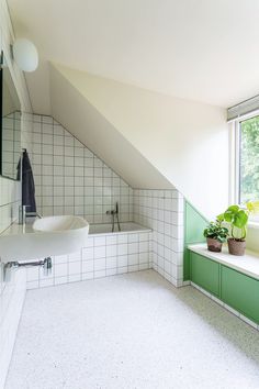 a bathroom with green and white tiles on the walls, windows, and bathtub