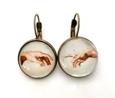 pair of earrings with the creation of jesus's hand painted on glass cabochles