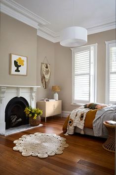 a bedroom with hardwood floors and a fireplace in the corner, along with a rug on the floor