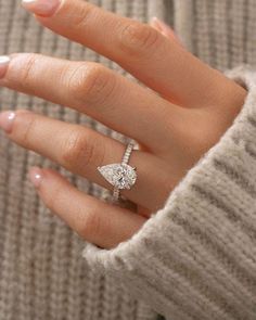 a woman's hand with a diamond ring on her finger and a white sweater