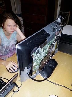 a woman sitting in front of a computer on top of a wooden desk next to a keyboard