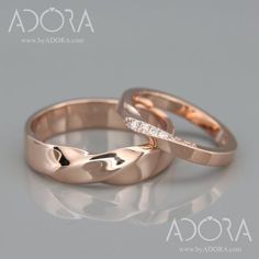 two gold wedding rings with diamonds on top of each other, sitting side by side