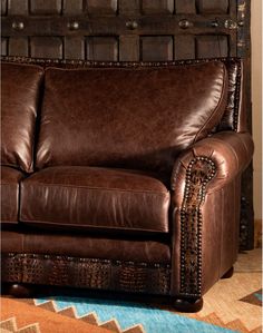 a brown leather couch sitting on top of a rug