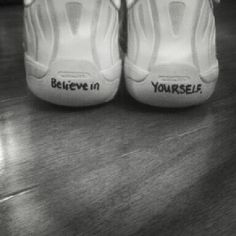 a pair of white shoes with the words believe in yourself written on them, sitting on a wooden floor