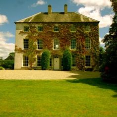 a large house with ivy growing on it's side and grass in the front yard