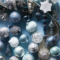 an assortment of christmas ornaments are arranged in a circular arrangement on a blue background with snowflakes and ribbons