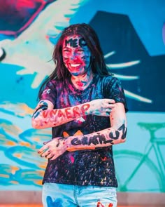 a man with long hair and face paint holding his arms out in front of him