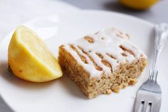 a white plate topped with a piece of cake next to a slice of lemon