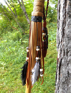 a tree with some feathers hanging from it's branches and beads on the bark