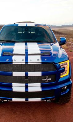 a blue truck with white stripes parked in the desert