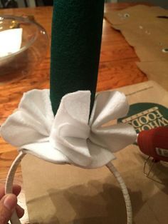 someone is making a paper flower on top of a piece of brown paper with a white ribbon