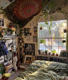 a bedroom with many plants and pictures on the wall above the bed, along with an open window