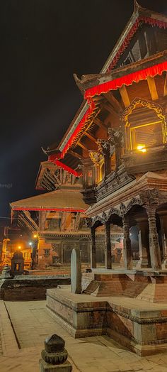 an ornate building lit up at night with red lights on the roof and pillars around it