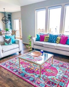 a living room with couches, chairs and rugs in front of large windows