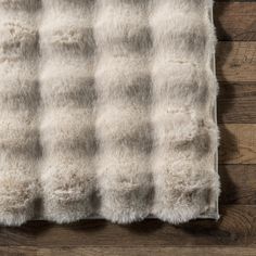 a white and brown plaid rug on top of a wooden floor