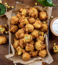 some fried food is sitting on a table next to other foods and dip sauces