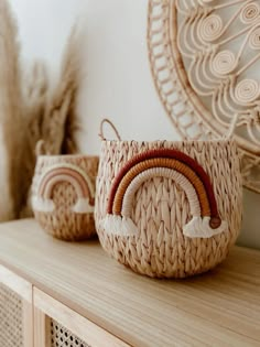 two woven baskets sitting on top of a wooden shelf next to a mirror and feathers