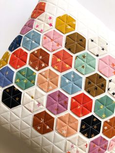 a close up of a colorful patchwork pillow on a white surface with small stars