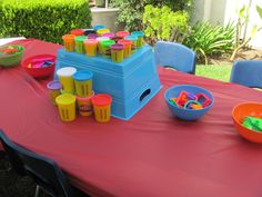 a red table topped with bowls and cups filled with plastic toys on top of it