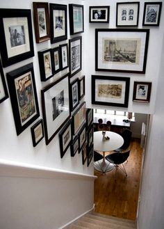 a staircase with pictures on the wall and stairs leading up to an upstairs dining area