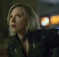 a woman with blonde hair wearing a black leather jacket and looking off into the distance