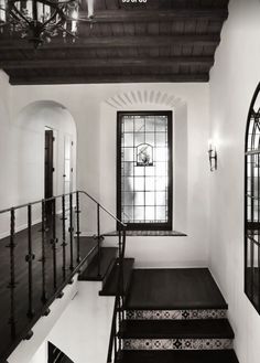 the stairs are black and white in this house with stained glass windows on each side