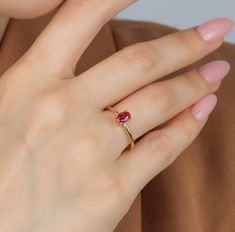 a woman wearing a gold ring with a red stone