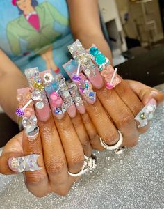 a woman is holding up her nails with different designs on them, including bows and crystal stones