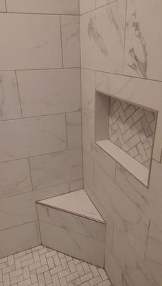 a walk in shower with white marble tile