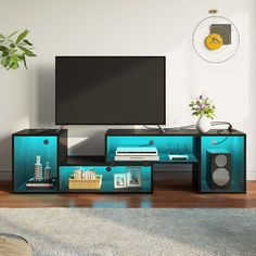 a living room with a large television on top of a blue entertainment center in front of a white wall