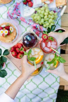 two people toasting with drinks and fruit on the table